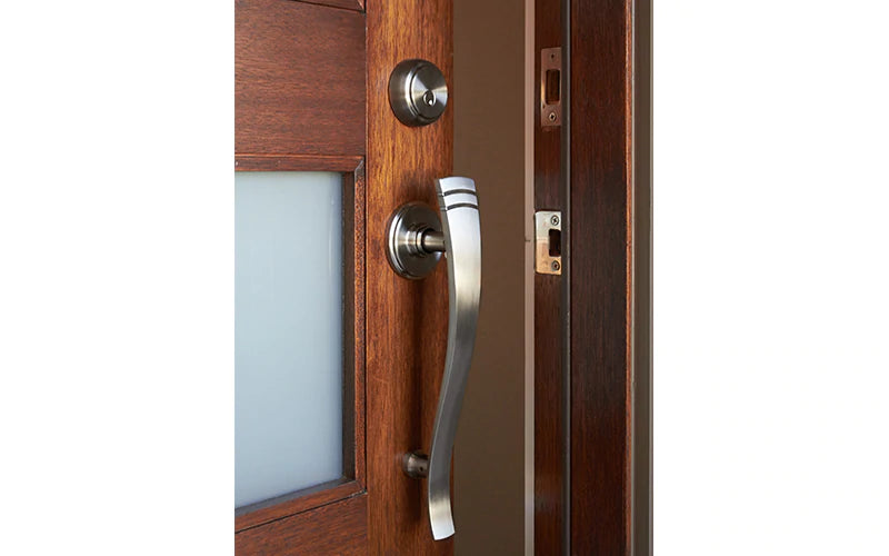 A silver door handle on a door slightly ajar.